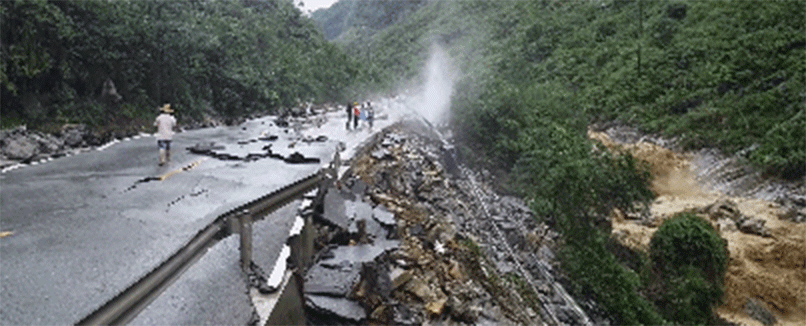 图为事发地点,山洪把路面的柏油层冲得支离破碎